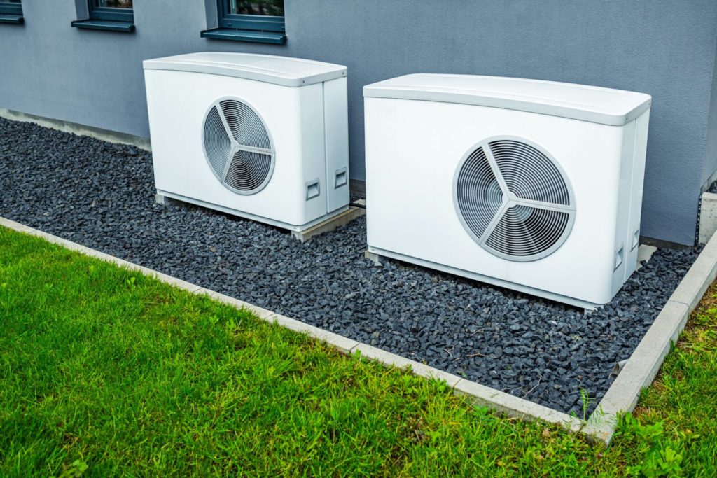 Two air source heat pumps installed outside of new and modern city house, green renewable energy